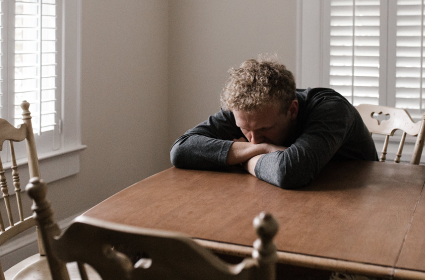 A man has his face buried in his arms, lamenting the loss of dice he's used maybe three times.