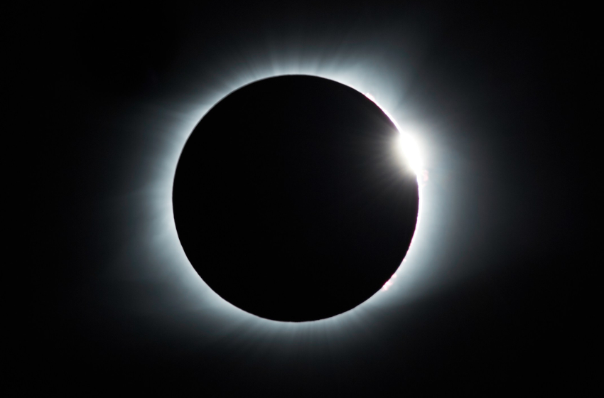 An image of the moon eclipsing the sun, with just a brief sliver of sun peeking out.